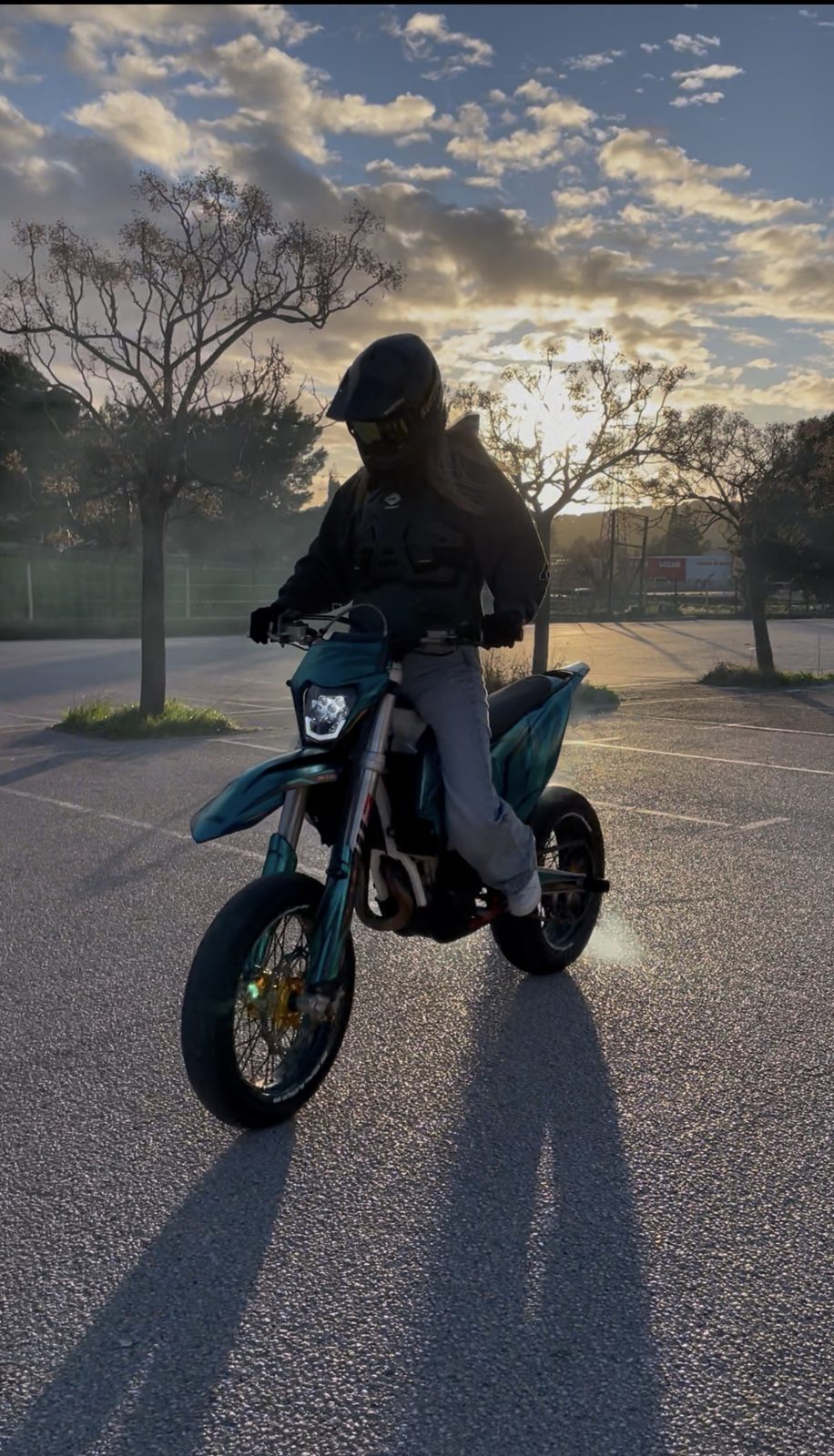 Alaïa sur sa moto à contre-jour sur un parking au coucher du soleil