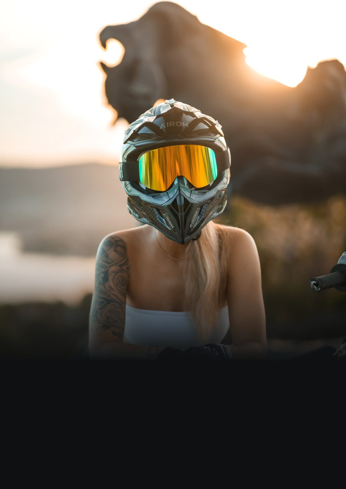 Alaïa Kskadeuz casquée, accoudée à sa supermotard turquoise au coucher du soleil